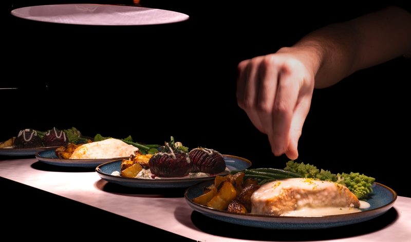 Dinner,Being,Served,On,A,Kitchen,Pass,Under,Lights